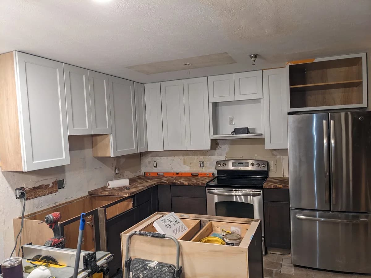 White shaker uppers and dark base cabinets in a kitchen mid-remodel