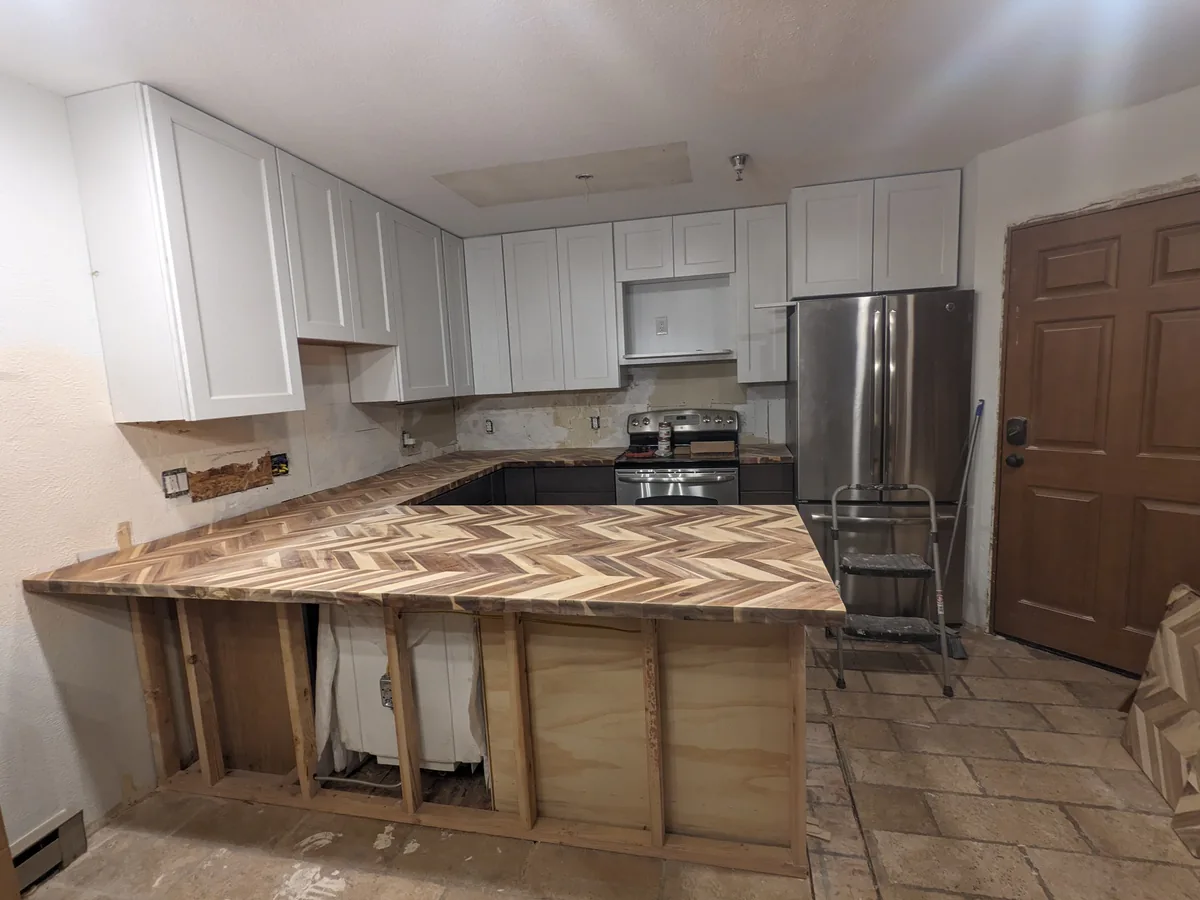 Chevron butcher-block counters on new base cabinets, the peninsula's frame still open, in Zack's Golden kitchen remodel