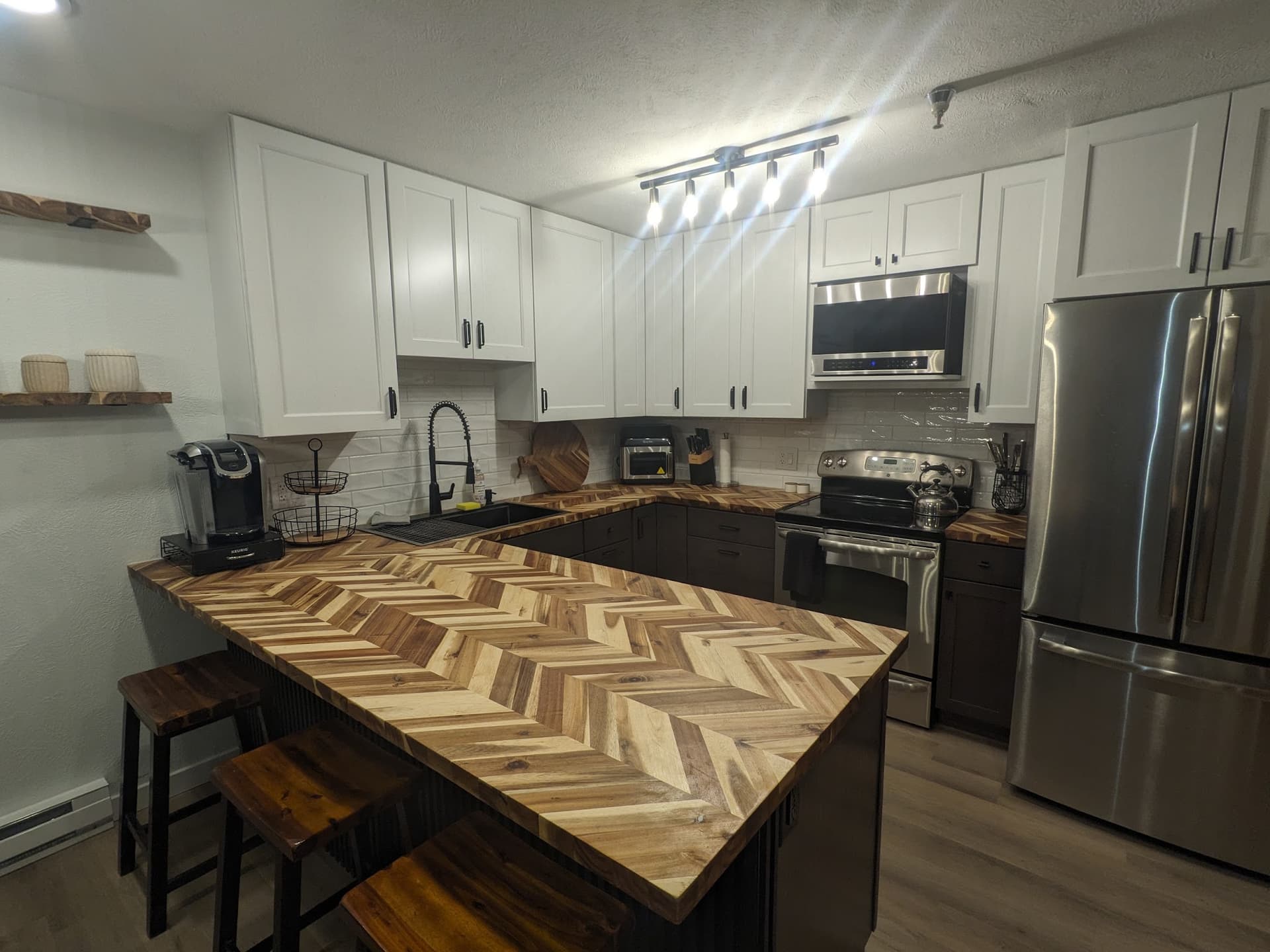 Remodeled kitchen with white shaker cabinets, a chevron butcher-block peninsula and a subway-tile backsplash