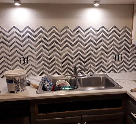 Chevron marble mosaic backsplash installed behind a kitchen sink