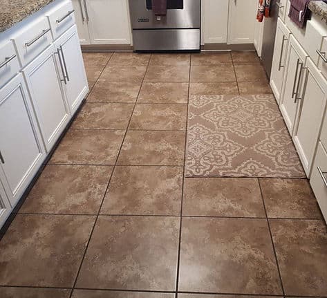 Tile floor laid in a kitchen between white cabinets